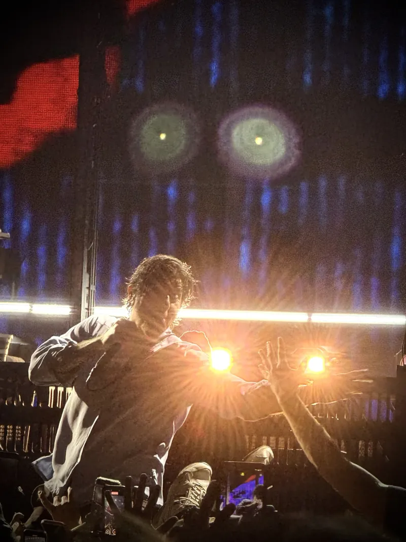 Chino Moreno performing in silhouette against glowing stage lights