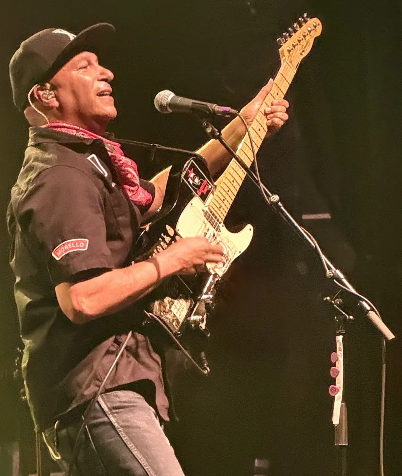 Tom Morello playing a Telecaster at the microphone in a black cap